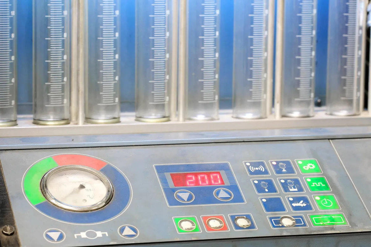 Fluid test bench with graduated glass cylinders, a pressure gauge and a digital control panel
